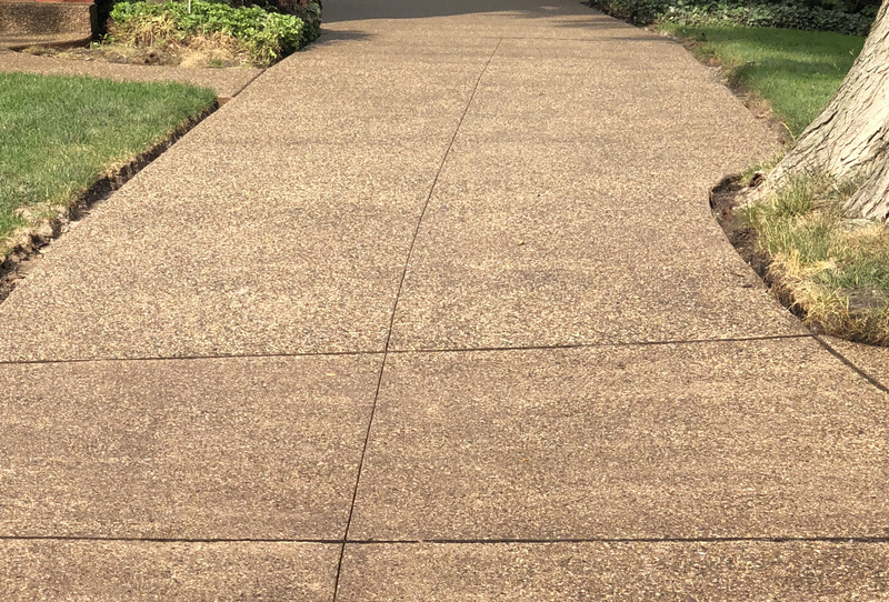 A freshly installed exposed aggregate concrete driveway with control joints, completed by expert concrete contractors.