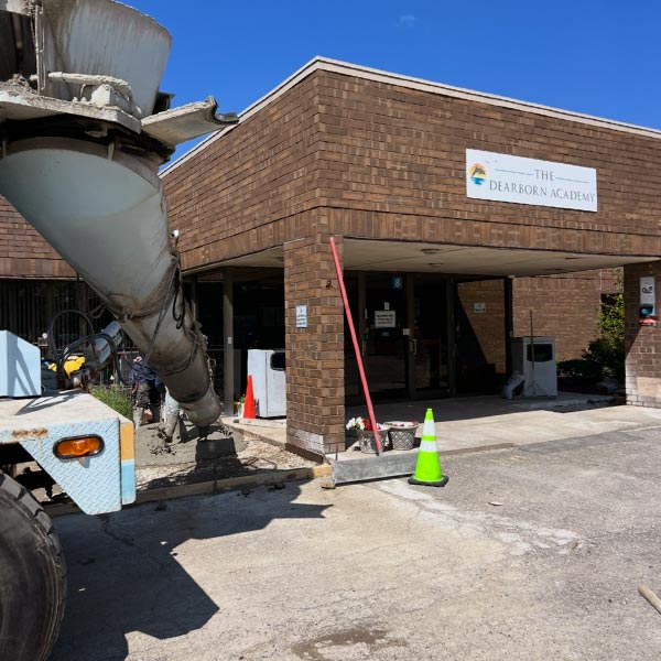 Concrete mixer truck pouring a new entrance and pavement for commercial parking lots at The Dearborn Academy.